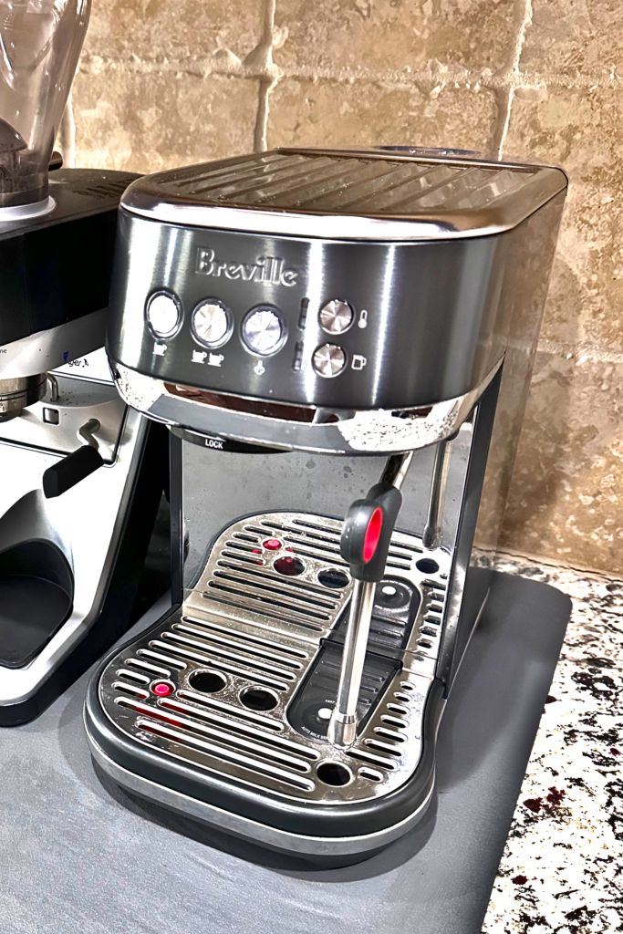 Breville Bambino Plus espresso machine with steam wand and control buttons on a kitchen countertop.
