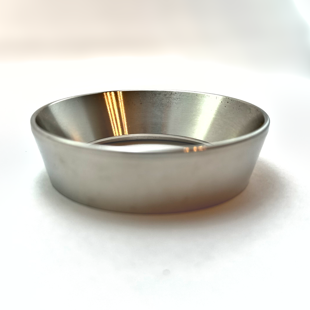 Metal espresso dosing funnel placed on a portafilter, used to keep all grounds contained during puck prep.